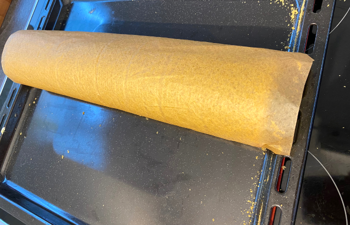 Den Teig vorsichtig mit Hilfe des Backpapiers aufrollen